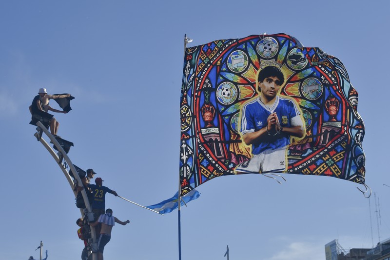Suasana para fans Argentina dengan spanduk Diego Maradona berkumpul merayakan kemenangan negaranya usai pertandingan sepak bola final Piala Dunia Qatar 2022 antara Argentina dan Prancis di Buenos Aires, Argentina Minggu (18/12/2022). Argentina menjadi juara Piala Dunia 2022 setelah menang adu penalti atas Prancis 4-2. (REUTERS/Agustin Marcarian)