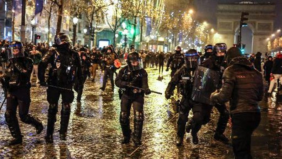 French police officers confront an individual on the Champs-Elysees as football fans gather after France's defeat in the final football match of the Qatar 2022 World Cup between Argentina and France in central Paris on December 18, 2022. (Photo by Charly TRIBALLEAU / AFP)