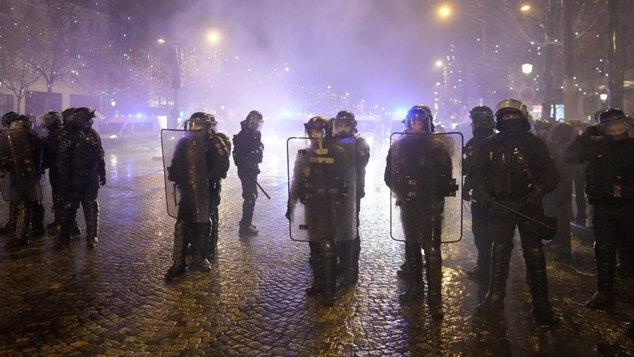 Seorang petugas polisi menendang seseorang setelah pertandingan final sepak bola Piala Dunia antara Argentina dan Prancis di jalan Champs-Elysees, Paris, Minggu (18/12/2022). Argentina telah memenangkan Piala Dunia dengan mengalahkan Prancis 4-2 dalam adu penalti di final. (AP Photo/Thibault Camus)