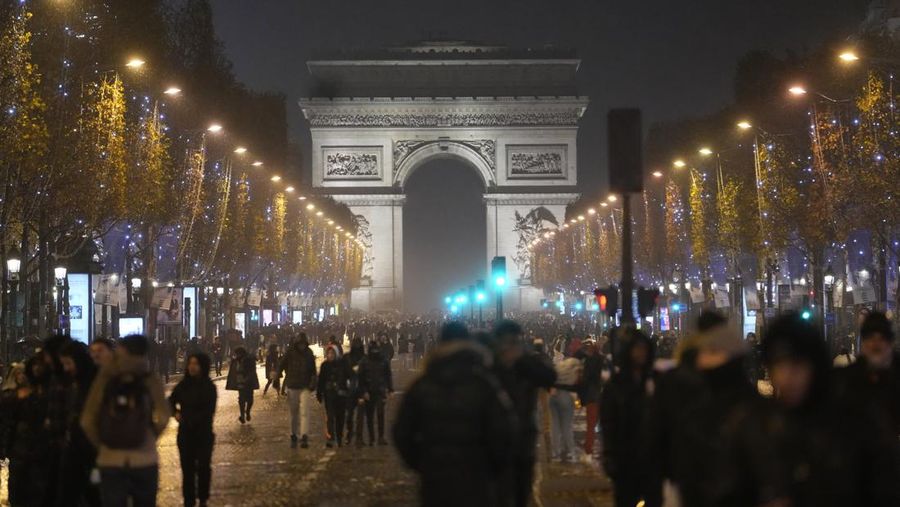 Seorang petugas polisi menendang seseorang setelah pertandingan final sepak bola Piala Dunia antara Argentina dan Prancis di jalan Champs-Elysees, Paris, Minggu (18/12/2022). Argentina telah memenangkan Piala Dunia dengan mengalahkan Prancis 4-2 dalam adu penalti di final. (AP Photo/Thibault Camus)