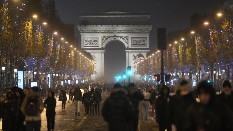 Seorang petugas polisi menendang seseorang setelah pertandingan final sepak bola Piala Dunia antara Argentina dan Prancis di jalan Champs-Elysees, Paris, Minggu (18/12/2022). Argentina telah memenangkan Piala Dunia dengan mengalahkan Prancis 4-2 dalam adu penalti di final. (AP Photo/Thibault Camus)