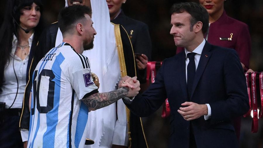 Penyerang #10 Argentina Lionel Messi disambut oleh Presiden Prancis Emmanuel Macron setelah menerima penghargaan Bola Emas pada upacara trofi Piala Dunia Qatar 2022 setelah pertandingan final sepak bola antara Argentina dan Prancis di Stadion Lusail di Lusail, utara Doha, Qatar, Minggu (18/12/2022). Argentina menjadi juara Piala Dunia 2022 setelah menang adu penalti atas Prancis 4-2. (Photo by FRANCK FIFE/AFP via Getty Images)