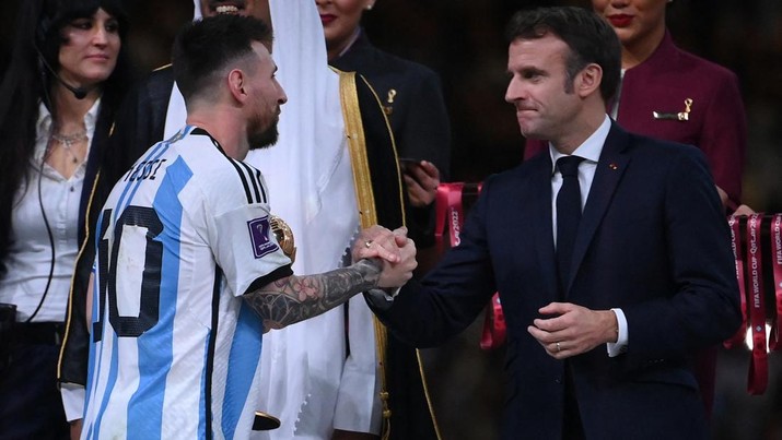 Penyerang #10 Argentina Lionel Messi disambut oleh Presiden Prancis Emmanuel Macron setelah menerima penghargaan Bola Emas pada upacara trofi Piala Dunia Qatar 2022 setelah pertandingan final sepak bola antara Argentina dan Prancis Penyerang #10 Argentina Lionel Messi disambut oleh Presiden Prancis Emmanuel Macron setelah menerima penghargaan Bola Emas pada upacara trofi Piala Dunia Qatar 2022 setelah pertandingan final sepak bola antara Argentina dan Prancis di Stadion Lusail di Lusail, utara Doha, Qatar, Minggu (18/12/2022). Argentina menjadi juara Piala Dunia 2022 setelah menang adu penalti atas Prancis 4-2. (Photo by FRANCK FIFE/AFP via Getty Images)