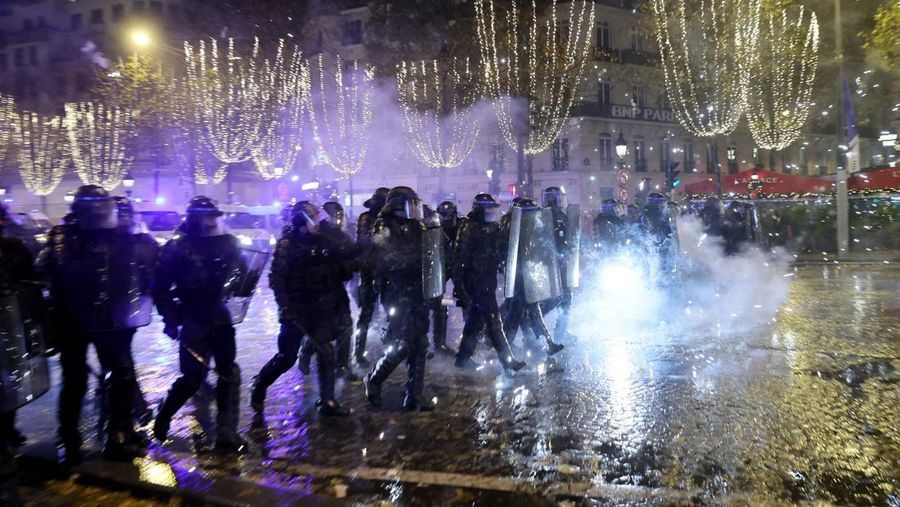 Seorang petugas polisi menendang seseorang setelah pertandingan final sepak bola Piala Dunia antara Argentina dan Prancis di jalan Champs-Elysees, Paris, Minggu (18/12/2022). Argentina telah memenangkan Piala Dunia dengan mengalahkan Prancis 4-2 dalam adu penalti di final. (AP Photo/Thibault Camus)
