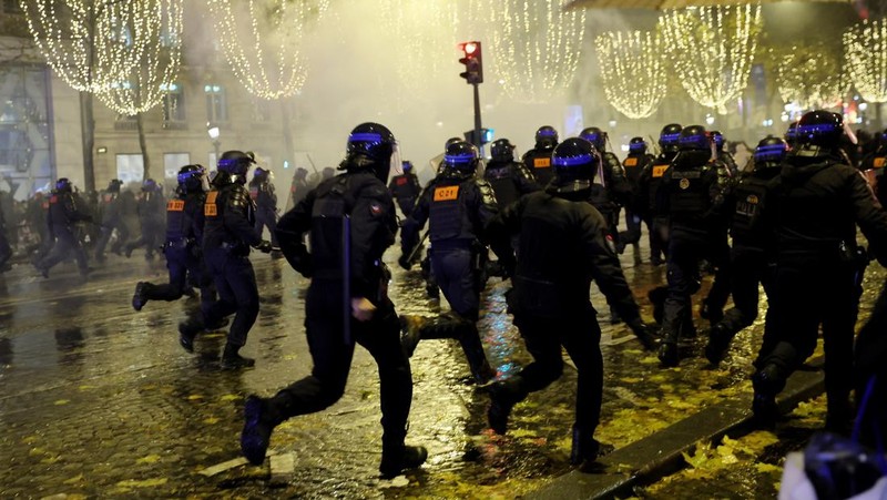 Seorang petugas polisi menendang seseorang setelah pertandingan final sepak bola Piala Dunia antara Argentina dan Prancis di jalan Champs-Elysees, Paris, Minggu (18/12/2022). Argentina telah memenangkan Piala Dunia dengan mengalahkan Prancis 4-2 dalam adu penalti di final. (AP Photo/Thibault Camus)