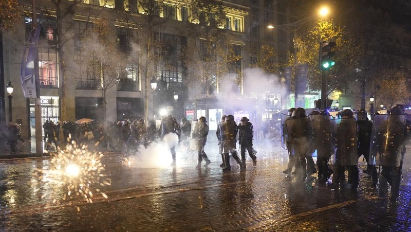 Seorang petugas polisi menendang seseorang setelah pertandingan final sepak bola Piala Dunia antara Argentina dan Prancis di jalan Champs-Elysees, Paris, Minggu (18/12/2022). Argentina telah memenangkan Piala Dunia dengan mengalahkan Prancis 4-2 dalam adu penalti di final. (AP Photo/Thibault Camus)