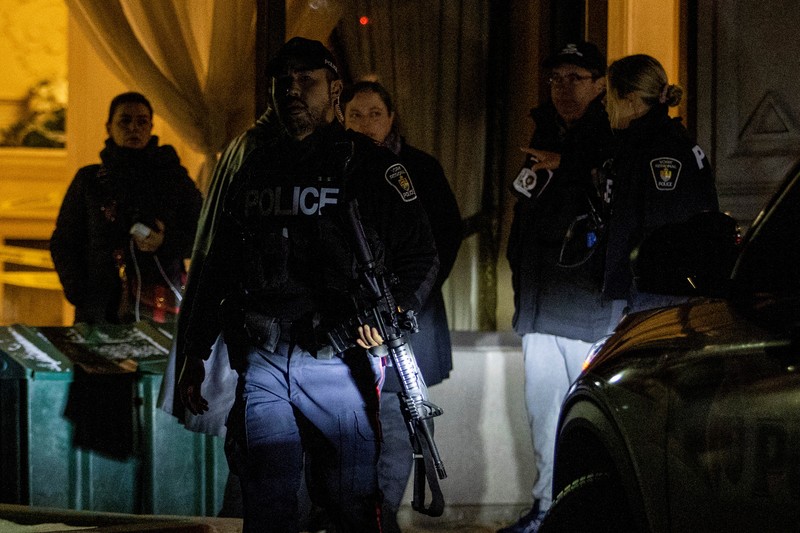 Seorang petugas polisi berjalan dengan senjata setelah penembakan massal yang fatal di sebuah gedung kondominium di pinggiran kota Toronto Vaughan, Ontario, Kanada 19 Desember 2022. (REUTERS/Carlos Osorio)