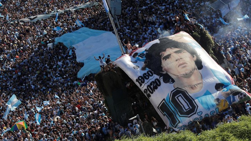 Suasana para fans Argentina dengan spanduk Diego Maradona berkumpul merayakan kemenangan negaranya usai pertandingan sepak bola final Piala Dunia Qatar 2022 antara Argentina dan Prancis di Buenos Aires, Argentina Minggu (18/12/2022). Argentina menjadi juara Piala Dunia 2022 setelah menang adu penalti atas Prancis 4-2. (REUTERS/Agustin Marcarian)