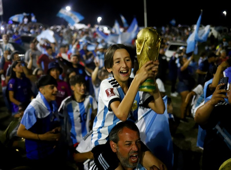Lionel Messi dari Argentina (Kiri) dan Lionel Scaloni (Kanan) memegang Piala Dunia FIFA saat kedatangan tim sepak bola nasional pria Argentina setelah memenangkan Piala Dunia FIFA Qatar 2022 pada 20 Desember 2022 di Buenos Aires, Argentina. (Marcelo Endelli/Getty Images)