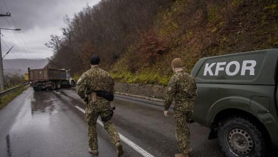 NATO soldiers serving in the peacekeeping mission in Kosovo (KFOR) inspect a road barricade set up by ethnic Serbs near the town of Zubin Potok on December 11, 2022. - Hundreds of ethnic Serbs erected barricades on a road in northern Kosovo on Saturday, blocking the traffic over the two main border crossings towards Serbia, police said. Trucks, ambulance cars and agricultural machines were used as roadblocks, heightening recent tensions which included explosions, shootings and an armed attack on a police patrol which saw one ethnic Albanian police officer wounded. (Photo by Armend NIMANI / AFP)