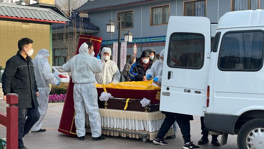 Pekerja dengan pakaian pelindung memindahkan jenazah dalam peti mati di rumah duka, di tengah wabah penyakit virus corona (COVID-19) di Beijing, China, 17 Desember 2022. (REUTERS/Alessandro Diviggiano)