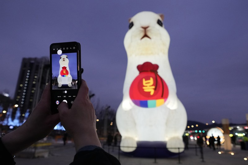 Seorang pengunjung mengambil foto lentera raksasa yang bersinar untuk perayaan Tahun Kelinci 2023 mendatang selama Festival Lentera di Lapangan Gwanghwamun di Seoul, Korea Selatan, Senin, 19 Desember 2022. Festival ini akan berlangsung dari 19 Desember hingga Desember 31. (AP Photo/Ahn Young-joon)
