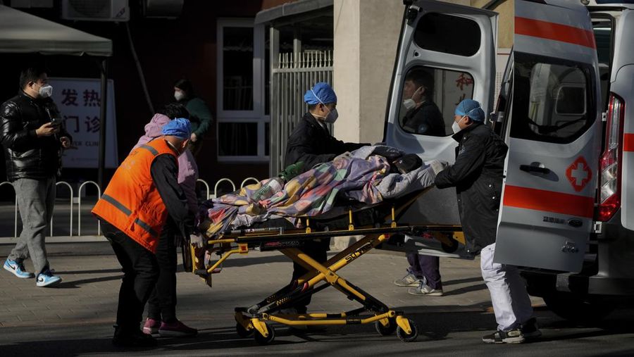 Seorang pasien didorong ke klinik demam di sebuah rumah sakit di Beijing, China, Senin (19/12/2022). China diprediksi bakal mengalami lonjakan kematian akibat Covid-19 hingga lebih dari satu juta kasus pada 2023 jika tren penularan virus corona terus melonjak. (AP Photo/Andy Wong)