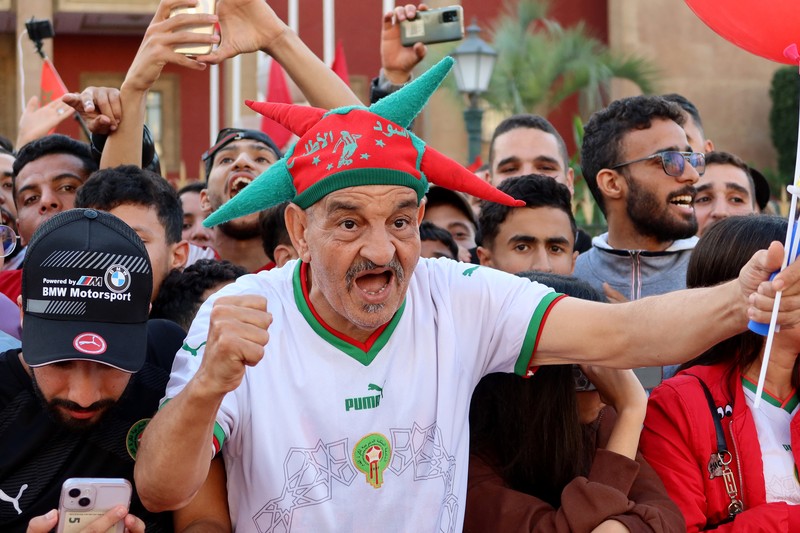 Pendukung bersorak dan menyalakan suar saat tim sepak bola nasional Maroko tiba di pusat ibu kota Rabat, pada 20 Desember 2022, setelah Piala Dunia Qatar 2022. (FADEL SENNA/AFP via Getty Images)