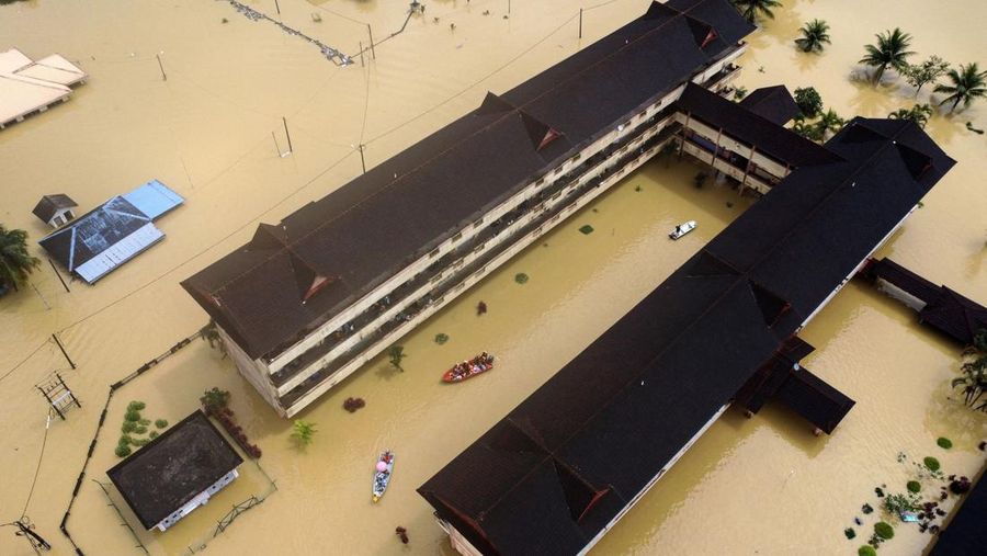 Penduduk diselamatkan dengan perahu dari pusat bantuan banjir saat air banjir naik dan sebagian bangunan terendam di Dungun, Terengganu, Malaysia 21 Desember 2022. Lebih dari 70.000 orang terpaksa mengungsi ke pusat bantuan, dengan jumlah yang meningkat di Kelantan, Terengganu dan Pahang, menurut media setempat. (REUTERS/Stringer)