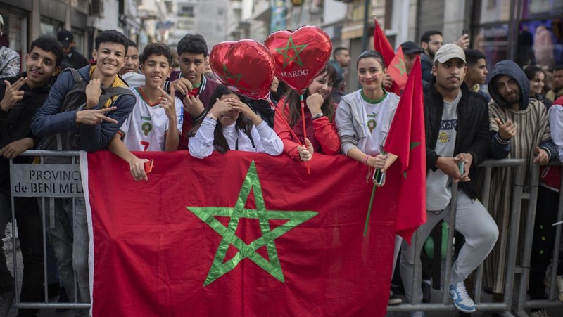 Pendukung bersorak dan menyalakan suar saat tim sepak bola nasional Maroko tiba di pusat ibu kota Rabat, pada 20 Desember 2022, setelah Piala Dunia Qatar 2022. (FADEL SENNA/AFP via Getty Images)