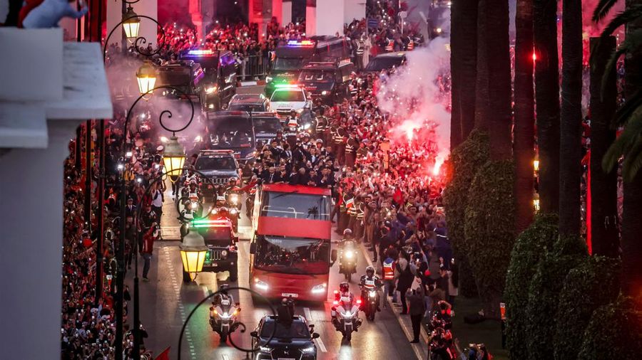 Pendukung bersorak dan menyalakan suar saat tim sepak bola nasional Maroko tiba di pusat ibu kota Rabat, pada 20 Desember 2022, setelah Piala Dunia Qatar 2022. (FADEL SENNA/AFP via Getty Images)