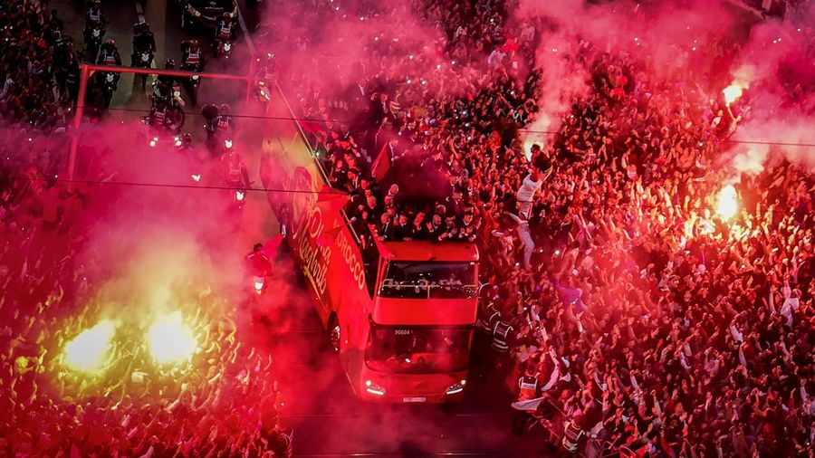 Pendukung bersorak dan menyalakan suar saat tim sepak bola nasional Maroko tiba di pusat ibu kota Rabat, pada 20 Desember 2022, setelah Piala Dunia Qatar 2022. (FADEL SENNA/AFP via Getty Images)