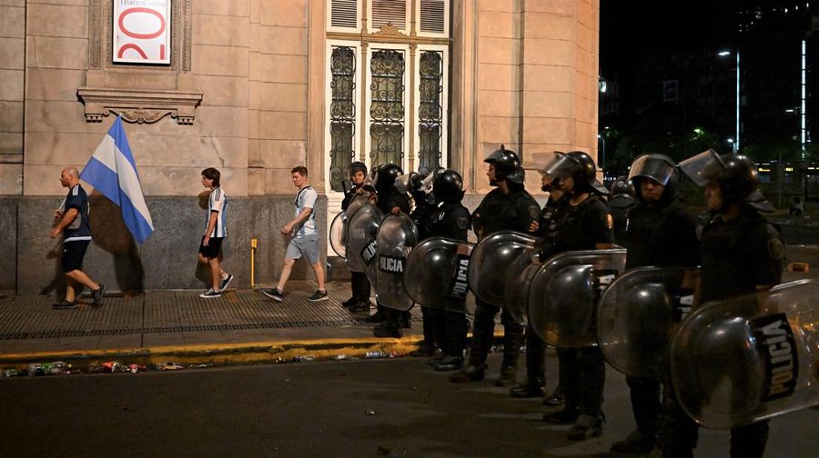 Seorang polisi anti huru hara menghadapi seorang penggemar Argentina selama bentrokan setelah perayaan kedatangan tim dari turnamen Piala Dunia Qatar 2022, yang membuat jutaan orang kecewa ketika parade bus beratap terbuka harus ditinggalkan karena kerumunan besar, pada 20 Desember, 2022, di sekitar Obelisk di Buenos Aires.  (LUIS ROBAYO/AFP via Getty Images)