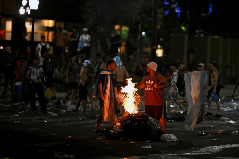 Seorang polisi anti huru hara menghadapi seorang penggemar Argentina selama bentrokan setelah perayaan kedatangan tim dari turnamen Piala Dunia Qatar 2022, yang membuat jutaan orang kecewa ketika parade bus beratap terbuka harus ditinggalkan karena kerumunan besar, pada 20 Desember, 2022, di sekitar Obelisk di Buenos Aires. Seorang polisi anti huru hara menghadapi seorang penggemar Argentina selama bentrokan setelah perayaan kedatangan tim dari turnamen Piala Dunia Qatar 2022, yang membuat jutaan orang kecewa ketika parade bus beratap terbuka harus ditinggalkan karena kerumunan besar, pada 20 Desember, 2022, di sekitar Obelisk di Buenos Aires. (LUIS ROBAYO/AFP via Getty Images)