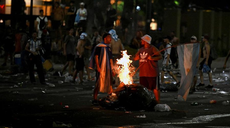 Seorang polisi anti huru hara menghadapi seorang penggemar Argentina selama bentrokan setelah perayaan kedatangan tim dari turnamen Piala Dunia Qatar 2022, yang membuat jutaan orang kecewa ketika parade bus beratap terbuka harus ditinggalkan karena kerumunan besar, pada 20 Desember, 2022, di sekitar Obelisk di Buenos Aires.  (LUIS ROBAYO/AFP via Getty Images)