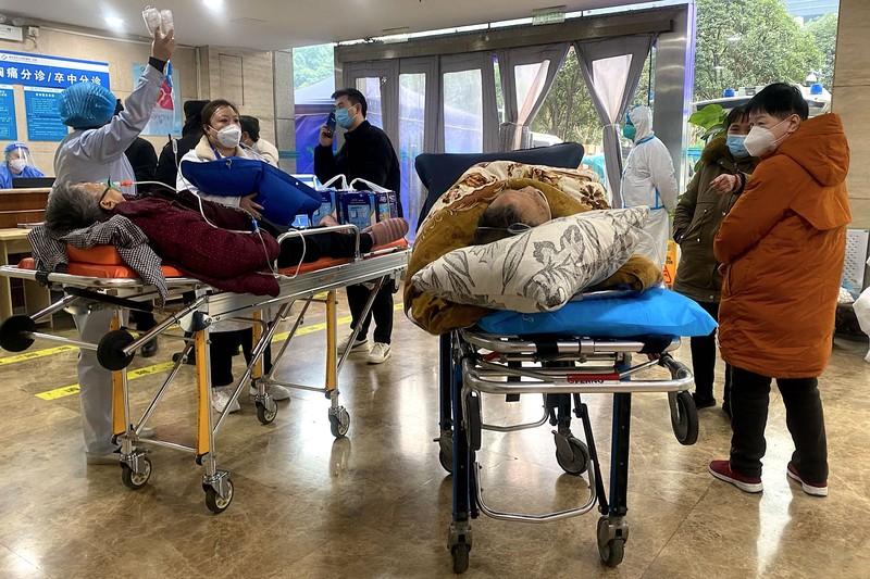 Pengemudi ambulans menurunkan pasien di luar klinik demam yang merawat pasien COVID-19 di Beijing, China, Rabu (21/12/2022). Kondisi pandemi Covid-19 di China terus memburuk seiring dengan berakhirnya kebijakan penguncian ketat di seluruh negeri. (Photo by Kevin Frayer/Getty Images)