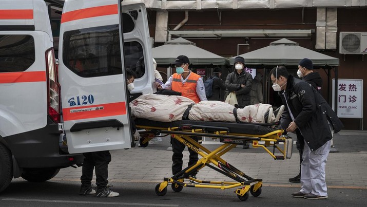 Kondisi pandemi Covid-19 di China Pengemudi ambulans menurunkan pasien di luar klinik demam yang merawat pasien COVID-19 di Beijing, China, Rabu (21/12/2022). Kondisi pandemi Covid-19 di China terus memburuk seiring dengan berakhirnya kebijakan penguncian ketat di seluruh negeri. (Photo by Kevin Frayer/Getty Images)