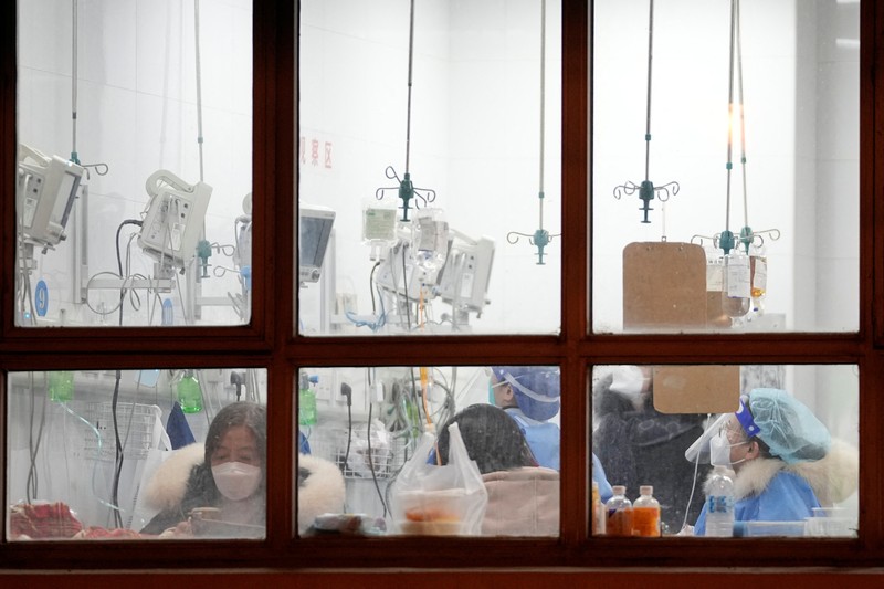Kondisi pandemi Covid-19 di China Pengemudi ambulans menurunkan pasien di luar klinik demam yang merawat pasien COVID-19 di Beijing, China, Rabu (21/12/2022). Kondisi pandemi Covid-19 di China terus memburuk seiring dengan berakhirnya kebijakan penguncian ketat di seluruh negeri. (Photo by Kevin Frayer/Getty Images)