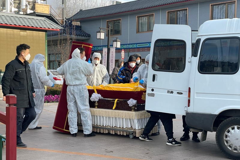 Pengemudi ambulans menurunkan pasien di luar klinik demam yang merawat pasien COVID-19 di Beijing, China, Rabu (21/12/2022). Kondisi pandemi Covid-19 di China terus memburuk seiring dengan berakhirnya kebijakan penguncian ketat di seluruh negeri. (Photo by Kevin Frayer/Getty Images)