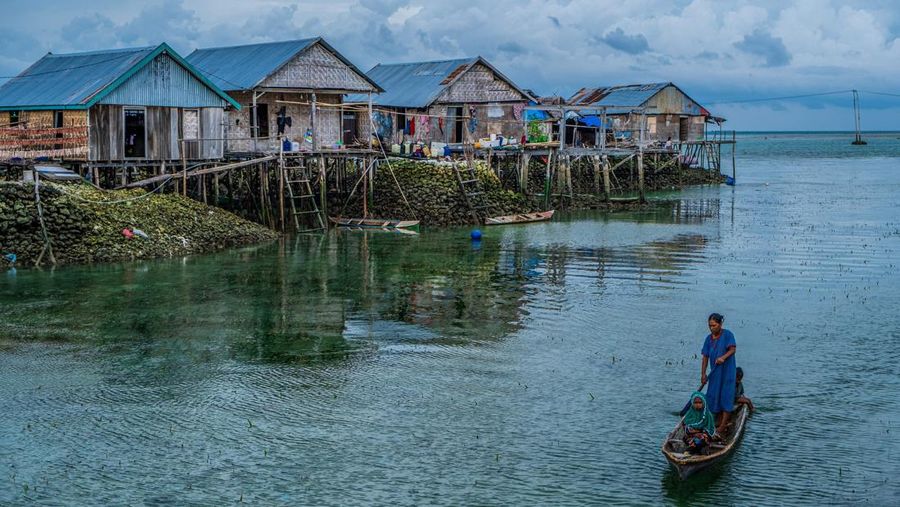 Seorang perempuan Bajo berdiri sambil mengayuh perahunya sambil mengantarkan anaknya ke sekolah. Orang Bajo adalah suku bangsa Indonesia yang hidup di laut di seluruh wilayah Indonesia.