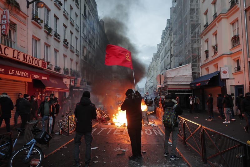 Police officers stand in a cloud of teargas as they clashes with members of Kurdish community near the crime scene where a shooting took place in Paris, Friday, Dec. 23, 2022. Skirmishes erupted in the neighbourhood a few hours after the shooting, as members of the Kurdish community shouted slogans against the Turkish government, and police fired tear gas to disperse an increasingly agitated crowd. A shooting targeting a Kurdish cultural center in Paris Friday left three people dead and three others wounded. (AP Photo/Lewis Joly)