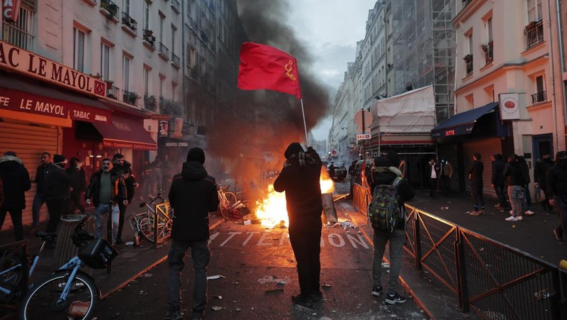 Police officers stand in a cloud of teargas as they clashes with members of Kurdish community near the crime scene where a shooting took place in Paris, Friday, Dec. 23, 2022. Skirmishes erupted in the neighbourhood a few hours after the shooting, as members of the Kurdish community shouted slogans against the Turkish government, and police fired tear gas to disperse an increasingly agitated crowd. A shooting targeting a Kurdish cultural center in Paris Friday left three people dead and three others wounded. (AP Photo/Lewis Joly)