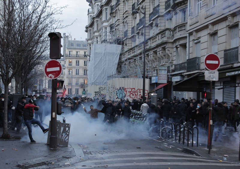 France Paris Shooting Police officers stand in a cloud of teargas as they clashes with members of Kurdish community near the crime scene where a shooting took place in Paris, Friday, Dec. 23, 2022. Skirmishes erupted in the neighbourhood a few hours after the shooting, as members of the Kurdish community shouted slogans against the Turkish government, and police fired tear gas to disperse an increasingly agitated crowd. A shooting targeting a Kurdish cultural center in Paris Friday left three people dead and three others wounded. (AP Photo/Lewis Joly)