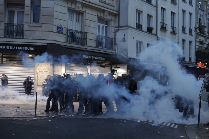 France Paris Shooting Police officers stand in a cloud of teargas as they clashes with members of Kurdish community near the crime scene where a shooting took place in Paris, Friday, Dec. 23, 2022. Skirmishes erupted in the neighbourhood a few hours after the shooting, as members of the Kurdish community shouted slogans against the Turkish government, and police fired tear gas to disperse an increasingly agitated crowd. A shooting targeting a Kurdish cultural center in Paris Friday left three people dead and three others wounded. (AP Photo/Lewis Joly)