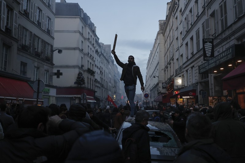 France Paris Shooting Police officers stand in a cloud of teargas as they clashes with members of Kurdish community near the crime scene where a shooting took place in Paris, Friday, Dec. 23, 2022. Skirmishes erupted in the neighbourhood a few hours after the shooting, as members of the Kurdish community shouted slogans against the Turkish government, and police fired tear gas to disperse an increasingly agitated crowd. A shooting targeting a Kurdish cultural center in Paris Friday left three people dead and three others wounded. (AP Photo/Lewis Joly)
