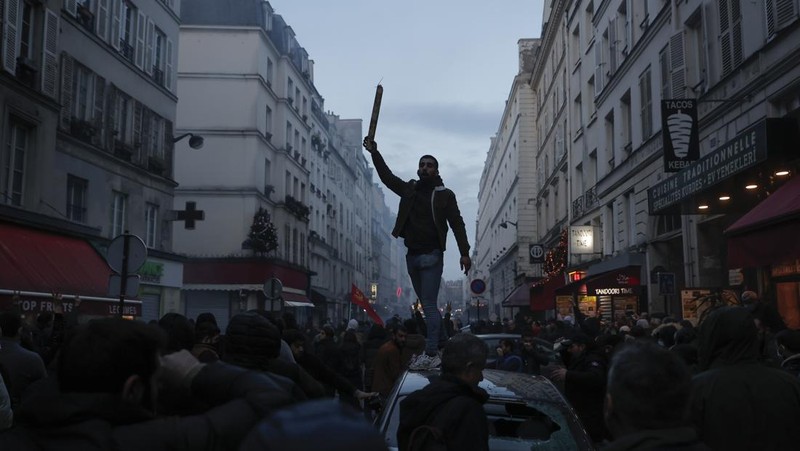 Police officers stand in a cloud of teargas as they clashes with members of Kurdish community near the crime scene where a shooting took place in Paris, Friday, Dec. 23, 2022. Skirmishes erupted in the neighbourhood a few hours after the shooting, as members of the Kurdish community shouted slogans against the Turkish government, and police fired tear gas to disperse an increasingly agitated crowd. A shooting targeting a Kurdish cultural center in Paris Friday left three people dead and three others wounded. (AP Photo/Lewis Joly)