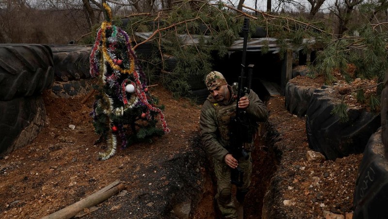 Prajurit Ukraina dengan resimen Polisi Patroli Tugas Khusus Dnipro-1 Raphael Karapitian 45, membawa pohon Natal yang dihias ke parit di garis depan, saat serangan Rusia terhadap Ukraina berlanjut, pada Malam Natal di Bakhmut, Ukraina, 24 Desember 2022. (REUTERS/Clodagh Kilcoyne)