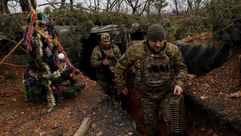 Prajurit Ukraina dengan resimen Polisi Patroli Tugas Khusus Dnipro-1 Raphael Karapitian 45, membawa pohon Natal yang dihias ke parit di garis depan, saat serangan Rusia terhadap Ukraina berlanjut, pada Malam Natal di Bakhmut, Ukraina, 24 Desember 2022. (REUTERS/Clodagh Kilcoyne)