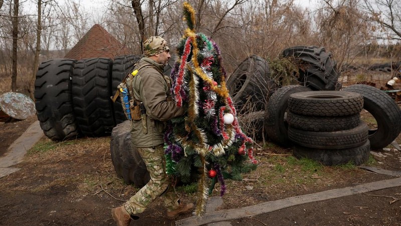 Prajurit Ukraina dengan resimen Polisi Patroli Tugas Khusus Dnipro-1 Raphael Karapitian 45, membawa pohon Natal yang dihias ke parit di garis depan, saat serangan Rusia terhadap Ukraina berlanjut, pada Malam Natal di Bakhmut, Ukraina, 24 Desember 2022. (REUTERS/Clodagh Kilcoyne)