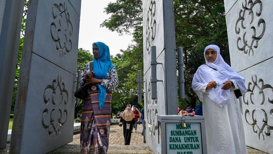 Seorang wanita berdoa di kuburan massal korban untuk memperingati 18 tahun tsunami Boxing Day 2004, di Banda Aceh pada 26 Desember 2022. (PCHAIDEER MAHYUDDIN / AFP)
