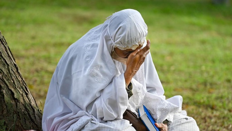 Seorang wanita berdoa di kuburan massal korban untuk memperingati 18 tahun tsunami Boxing Day 2004, di Banda Aceh pada 26 Desember 2022. (PCHAIDEER MAHYUDDIN / AFP)