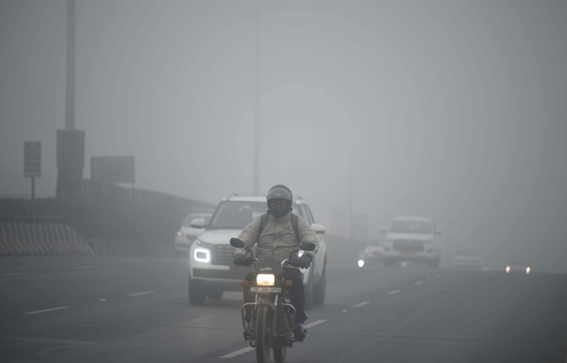 Orang-orang pergi ke tempat kerja mereka mengenakan pakaian hangat di tengah pagi kabut yang dingin dan tebal di sebuah jalan dekat Sekretariat Mini pada 26 Desember 2022 di Gurugram, India. Kabut tebal menyelimuti wilayah ibu kota nasional pada Senin pagi saat kota itu bergulat dengan kondisi gelombang dingin dengan suhu minimum yang cenderung turun hingga 4 derajat Celcius, menurut ramalan cuaca oleh Departemen Meteorologi India (IMD). (Photo by Parveen Kumar/Hindustan Times via Getty Images)