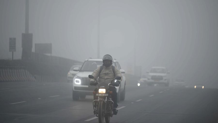 Orang-orang pergi ke tempat kerja mereka mengenakan pakaian hangat di tengah pagi kabut yang dingin dan tebal di sebuah jalan dekat Sekretariat Mini pada 26 Desember 2022 di Gurugram, India. Kabut tebal menyelimuti wilayah ibu kota nasional pada Senin pagi saat kota itu bergulat dengan kondisi gelombang dingin dengan suhu minimum yang cenderung turun hingga 4 derajat Celcius, menurut ramalan cuaca oleh Departemen Meteorologi India (IMD). (Photo by Parveen Kumar/Hindustan Times via Getty Images)