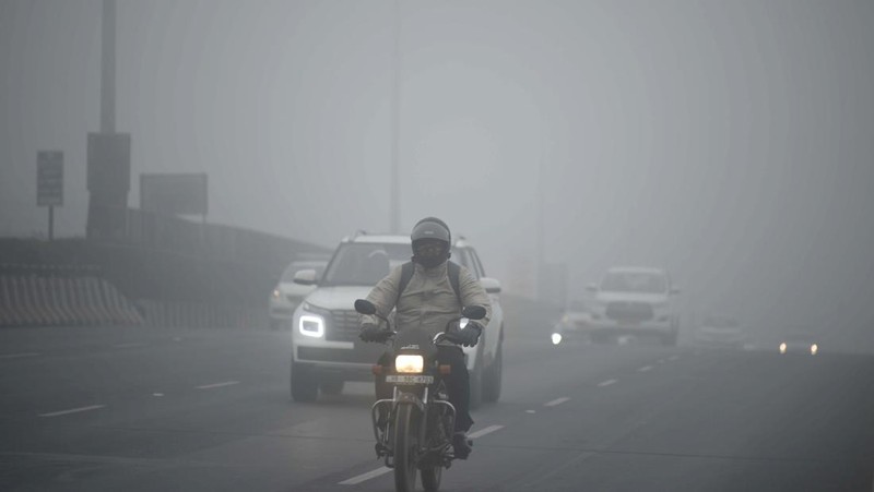 Orang-orang pergi ke tempat kerja mereka mengenakan pakaian hangat di tengah pagi kabut yang dingin dan tebal di sebuah jalan dekat Sekretariat Mini pada 26 Desember 2022 di Gurugram, India. Kabut tebal menyelimuti wilayah ibu kota nasional pada Senin pagi saat kota itu bergulat dengan kondisi gelombang dingin dengan suhu minimum yang cenderung turun hingga 4 derajat Celcius, menurut ramalan cuaca oleh Departemen Meteorologi India (IMD). (Photo by Parveen Kumar/Hindustan Times via Getty Images)