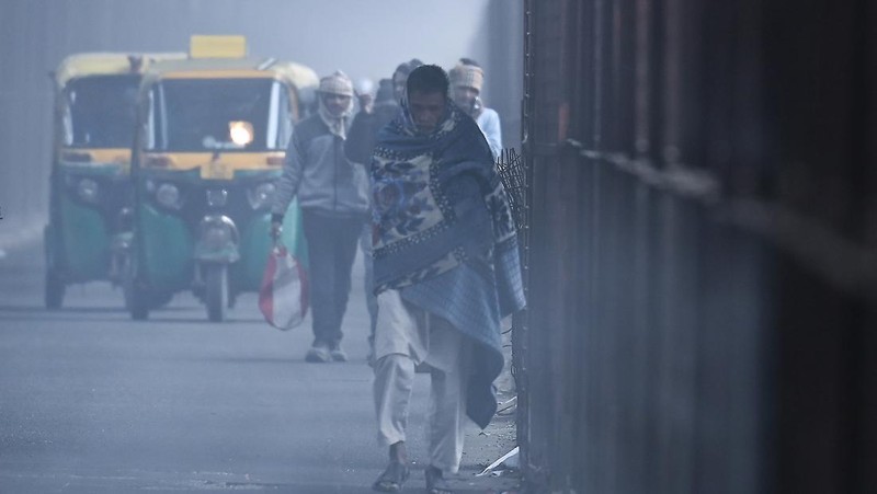 Orang-orang pergi ke tempat kerja mereka mengenakan pakaian hangat di tengah pagi kabut yang dingin dan tebal di sebuah jalan dekat Sekretariat Mini pada 26 Desember 2022 di Gurugram, India. Kabut tebal menyelimuti wilayah ibu kota nasional pada Senin pagi saat kota itu bergulat dengan kondisi gelombang dingin dengan suhu minimum yang cenderung turun hingga 4 derajat Celcius, menurut ramalan cuaca oleh Departemen Meteorologi India (IMD). (Photo by Parveen Kumar/Hindustan Times via Getty Images)