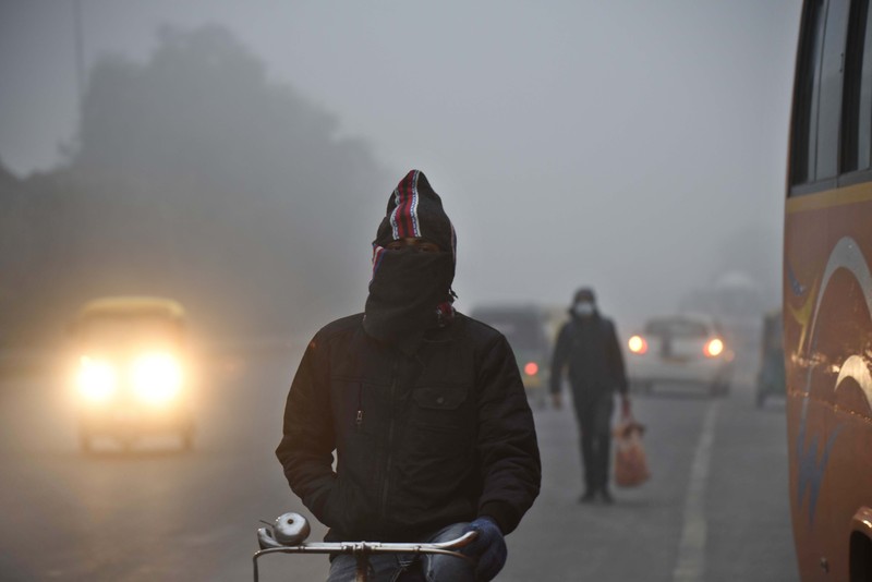 Orang-orang pergi ke tempat kerja mereka mengenakan pakaian hangat di tengah pagi kabut yang dingin dan tebal di sebuah jalan dekat Sekretariat Mini pada 26 Desember 2022 di Gurugram, India. Kabut tebal menyelimuti wilayah ibu kota nasional pada Senin pagi saat kota itu bergulat dengan kondisi gelombang dingin dengan suhu minimum yang cenderung turun hingga 4 derajat Celcius, menurut ramalan cuaca oleh Departemen Meteorologi India (IMD). (Photo by Parveen Kumar/Hindustan Times via Getty Images)