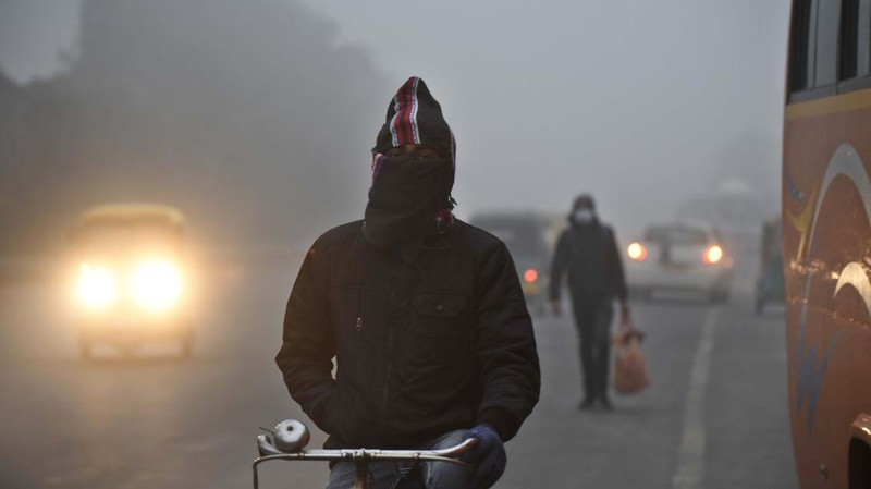 Orang-orang pergi ke tempat kerja mereka mengenakan pakaian hangat di tengah pagi kabut yang dingin dan tebal di sebuah jalan dekat Sekretariat Mini pada 26 Desember 2022 di Gurugram, India. Kabut tebal menyelimuti wilayah ibu kota nasional pada Senin pagi saat kota itu bergulat dengan kondisi gelombang dingin dengan suhu minimum yang cenderung turun hingga 4 derajat Celcius, menurut ramalan cuaca oleh Departemen Meteorologi India (IMD). (Photo by Parveen Kumar/Hindustan Times via Getty Images)