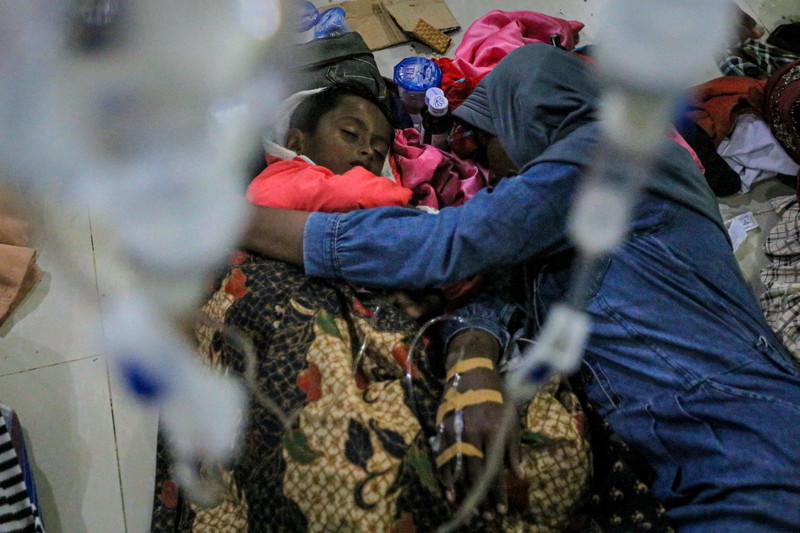 Foto yang diambil pada 26 Desember 2022 ini memperlihatkan para pria Rohingya sedang beristirahat di sebuah penampungan di distrik Muara Tiga di Pidie, provinsi Aceh. - Pengungsi Rohingya menerima perawatan medis darurat setelah sebuah kapal yang membawa hampir 200 orang mendarat di Indonesia pada 26 Desember, kata pihak berwenang, dalam pendaratan keempat di negara tersebut dalam beberapa bulan terakhir. (AMANDA JUFRIAN/AFP via Getty Images)