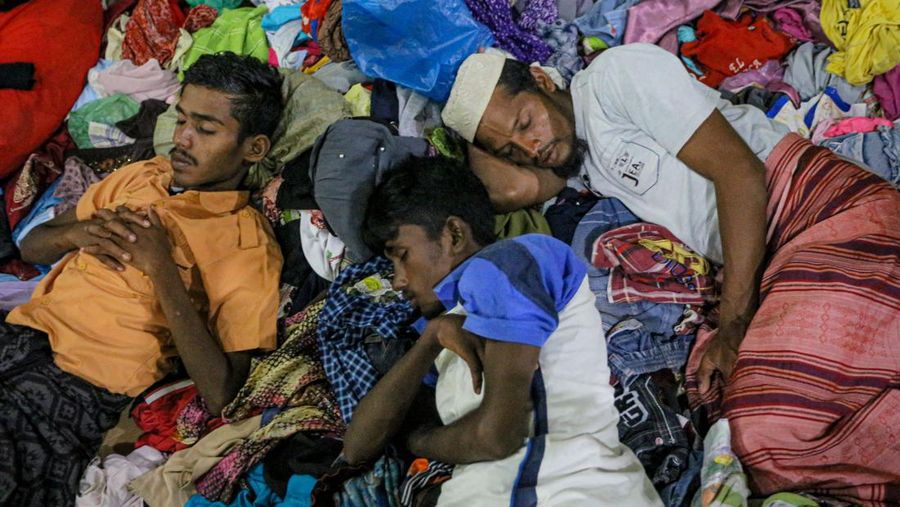 Foto yang diambil pada 26 Desember 2022 ini memperlihatkan para pria Rohingya sedang beristirahat di sebuah penampungan di distrik Muara Tiga di Pidie, provinsi Aceh. - Pengungsi Rohingya menerima perawatan medis darurat setelah sebuah kapal yang membawa hampir 200 orang mendarat di Indonesia pada 26 Desember, kata pihak berwenang, dalam pendaratan keempat di negara tersebut dalam beberapa bulan terakhir. (AMANDA JUFRIAN/AFP via Getty Images)