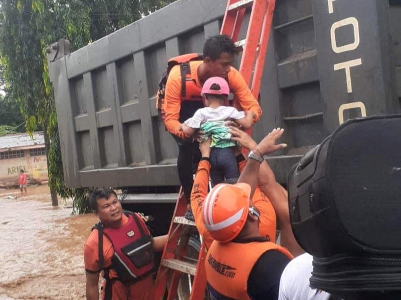 Petugas penyelamat membantu korban banjir di Plaridel, Misamis Occidental Province, Filipina, (26/12/2022). (via REUTERS/PHILIPPINE COAST GUARD)